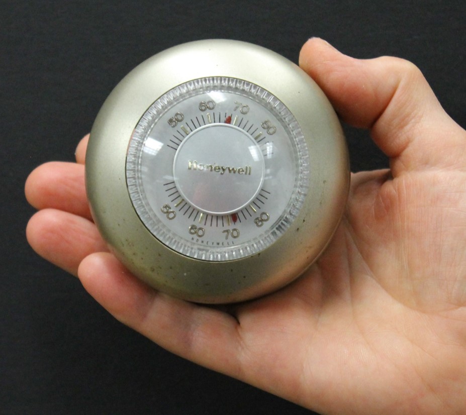 Silver thermostat with a dial.